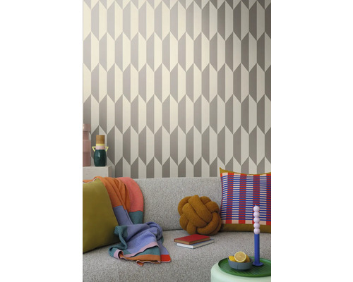 Salon avec papier peint géométrique gris et blanc derrière un canapé gris