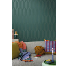 Salon avec un canapé gris, des coussins, des couvertures et du papier peint à motifs pour un intérieur élégant.