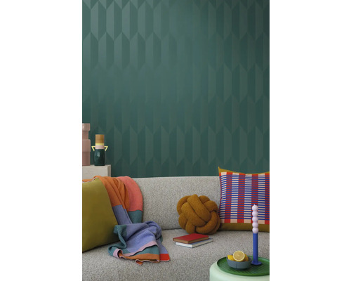 Salon avec un canapé gris, des coussins, des couvertures et du papier peint à motifs pour un intérieur élégant.