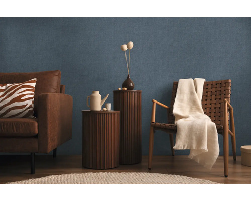 Salon avec canapé, fauteuil, tables d'appoint et décoration sur papier peint bleu texturé