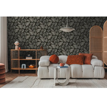 Salon avec canapé, table d'appoint et étagère devant un papier peint à motifs de feuilles