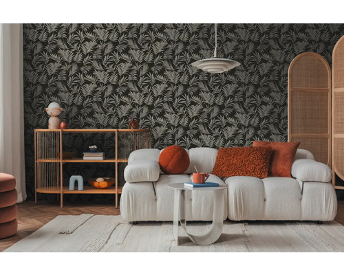 Salon avec canapé, table d'appoint et étagère devant un papier peint à motifs de feuilles