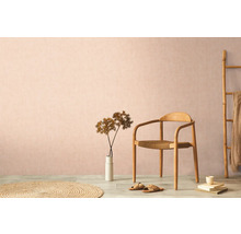 Dekoratives Wohnambiente mit Holzstuhl, Teppich und Zimmerpflanze vor einer dezenten Wand