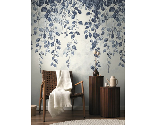 Papier peint décoratif avec motif de feuilles dans un salon élégant avec fauteuil et tables d'appoint.