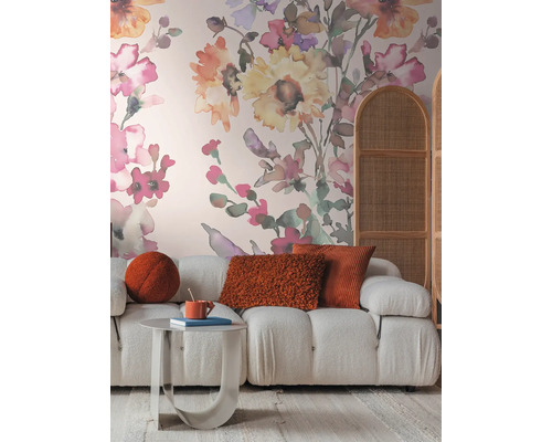 Salon avec canapé, table, coussins et papier peint floral pour une ambiance chaleureuse