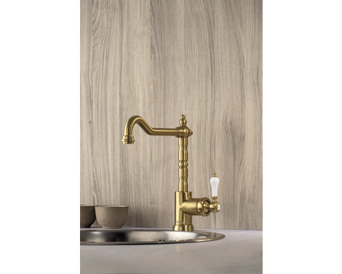 Goldfarbene Küchenarmatur mit weißem Griff montiert in einer Spüle