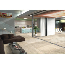 Espace de vie lumineux avec carrelage, canapé, table et coin cuisine.