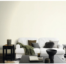 Wohnzimmer mit Sofa, Tisch und dekorativen Elementen vor einer gestrichenen Wand.