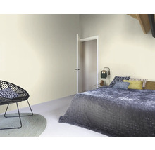 Helles Schlafzimmer mit Bett, Sessel und Tür