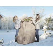 Deux personnes emballent des plantes dans un sac de protection hivernale dans un jardin enneigé.
