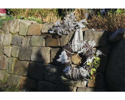 Couronne de l'Avent décorative avec ruban et motifs de Noël sur un mur de pierre