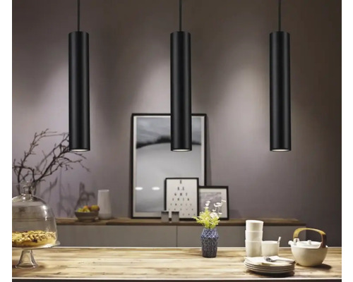Trois suspensions noires au-dessus d'une table dans une salle à manger.