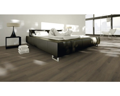 Schlafzimmer mit Laminatboden, Bett und Nachttischlampe.