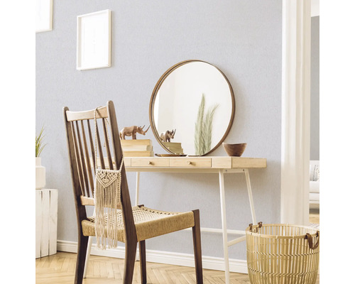 Scène décorative avec un bureau, une chaise, un miroir et des accessoires dans une pièce lumineuse.