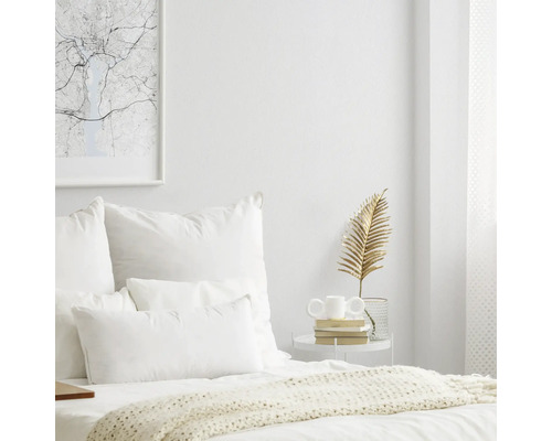 Chambre claire avec lit, oreillers, table d'appoint et objets de décoration