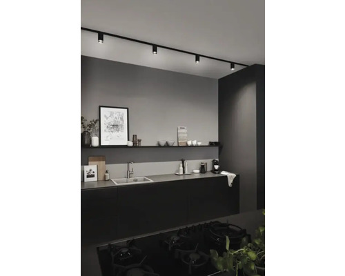 Cuisine moderne avec kitchenette noire, évier, étagère et système de rail noir avec spots.