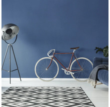Wohnzimmer mit Stehlampe, Fahrrad und Teppich im grafischen Design