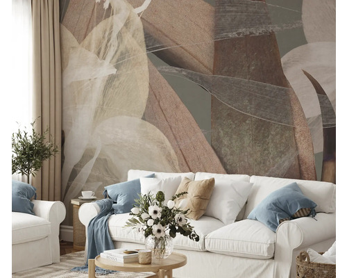 Wohnzimmer mit abstraktem Blättermuster an der Wand hinter einem weißen Sofa.