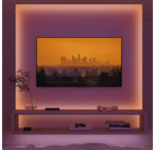 Salon avec télévision, étagères et éclairage d'ambiance.