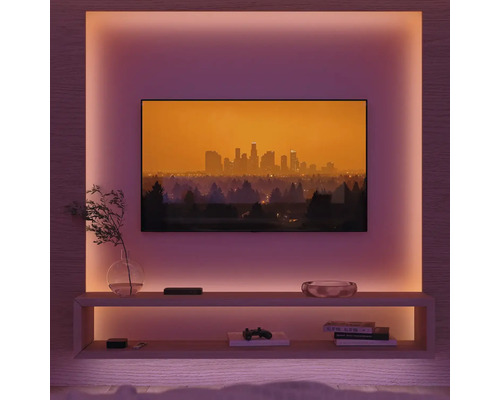 Salon avec télévision, étagères et éclairage d'ambiance.