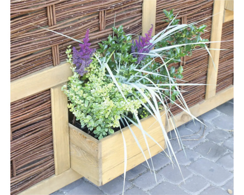 Bac à fleurs en bois avec des plantes devant une clôture tressée