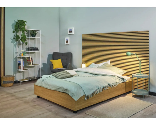 Chambre avec lit, table de chevet, lampe, fauteuil et bibliothèque