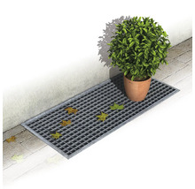 Gitterrinne mit Laub und einem Blumentopf auf Pflastersteinen