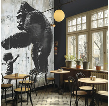 Innenraum eines Cafés mit einem Wandbild eines Gorillas und einem Kind, Tischen und Stühlen.