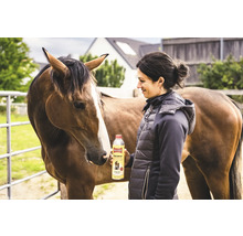 Femme tenant de l'huile de soin pour animaux Ballistol Animal à côté d'un cheval