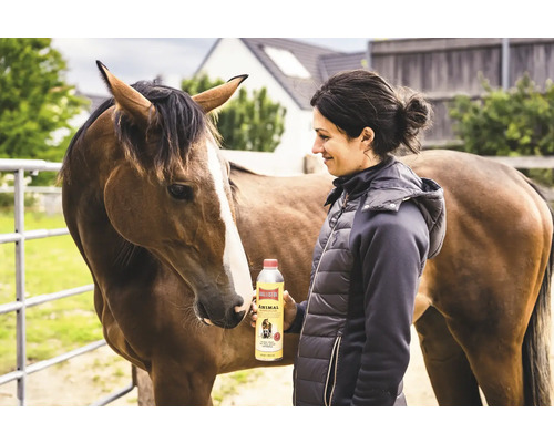 Femme tenant de l'huile de soin pour animaux Ballistol Animal à côté d'un cheval