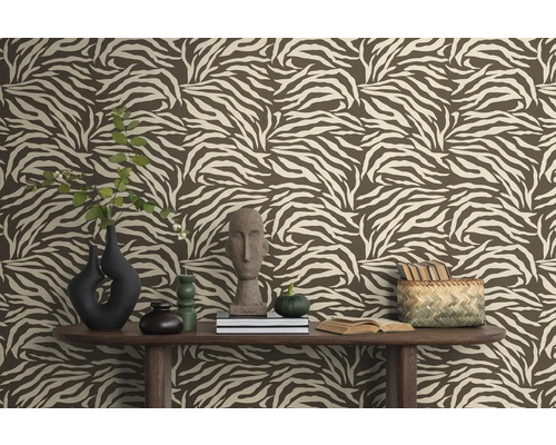 Vue d'une pièce avec du papier peint à motif zébré marron, décorée de vases, de livres et de décorations sur une table en bois.