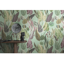 Gros plan d'un mur avec un papier peint à motifs de feuilles, une table avec un livre, une figurine décorative et une assiette.