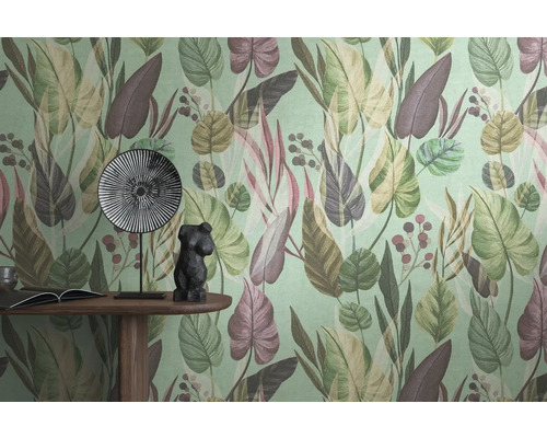 Gros plan d'un mur avec un papier peint à motifs de feuilles, une table avec un livre, une figurine décorative et une assiette.