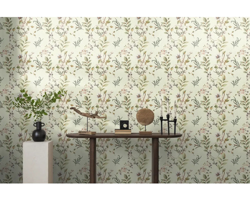 Pièce lumineuse avec papier peint à feuilles et décorations sur une table en bois.