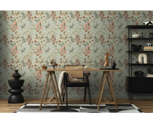 Ein Arbeitszimmer mit einem Schreibtisch vor einer Wand mit floral gemusterter Tapete.