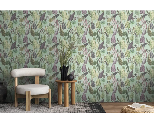 Une pièce avec un papier peint à motifs de feuilles, une chaise et une table d'appoint.