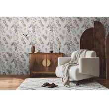 Wohnzimmer mit Blumentapete, Holzkommode, Sessel und Teppich für eine gemütliche Atmosphäre.