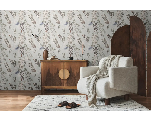 Wohnzimmer mit Blumentapete, Holzkommode, Sessel und Teppich für eine gemütliche Atmosphäre.