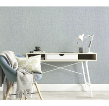 Helles Arbeitszimmer mit Schreibtisch, Stuhl und Lampe vor einer strukturierten Tapete