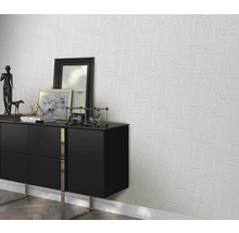 Wohnszene mit einer schwarzen Kommode und einer Tapete mit geometrischem Muster