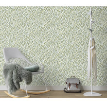 Zimmer mit einer Tapete mit Blattmuster, einem Schaukelstuhl und einer Garderobe.