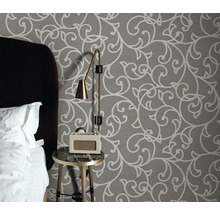 Chambre avec papier peint à motifs, table de chevet, lampe et radio-réveil