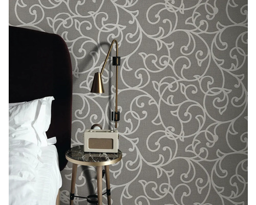 Chambre avec papier peint à motifs, table de chevet, lampe et radio-réveil