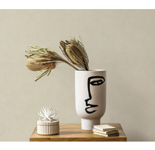 Scène décorative avec vase avec impression de visage, fleurs séchées, boîte à bijoux et livres sur une table en bois