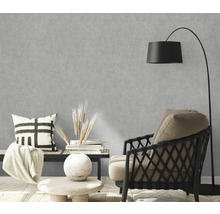 Wohnzimmer mit grauer Betonoptik-Tapete, Sessel und Stehlampe