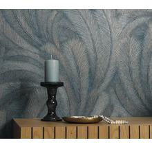 Mur décoratif avec papier peint à plumes, bougie et bijoux sur commode