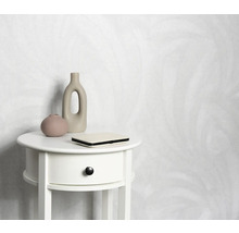 Papier peint clair à motifs derrière une table de chevet blanche avec décoration