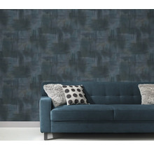 Papier peint à motifs derrière un canapé bleu avec des coussins