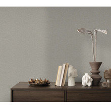 Gros plan d'un papier peint structuré gris au-dessus d'une commode avec des objets de décoration.