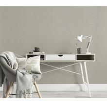 Raumszene mit Schreibtisch, Stuhl mit Decke und Kissen vor einer strukturierten Tapete